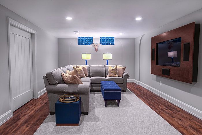 A living room with a couch , ottoman , and television.