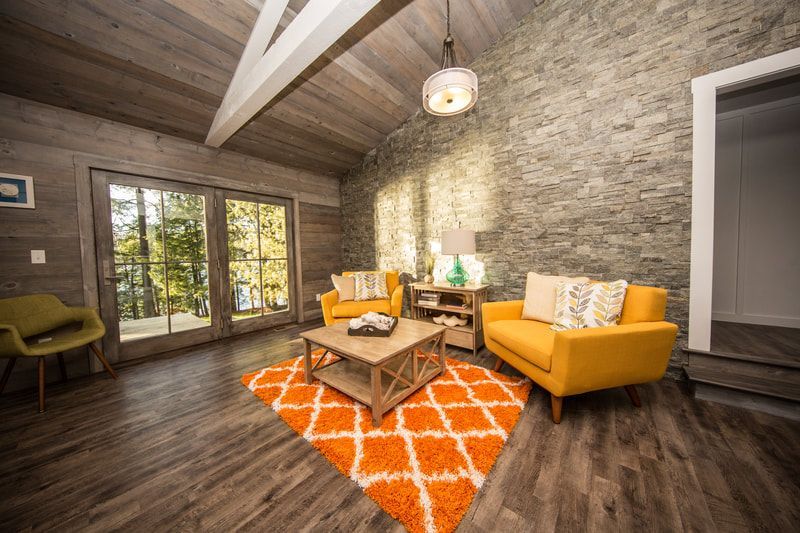 A living room with two yellow chairs , a coffee table , and a rug.