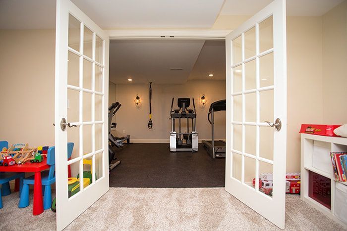 A basement with a treadmill and a table and chairs.