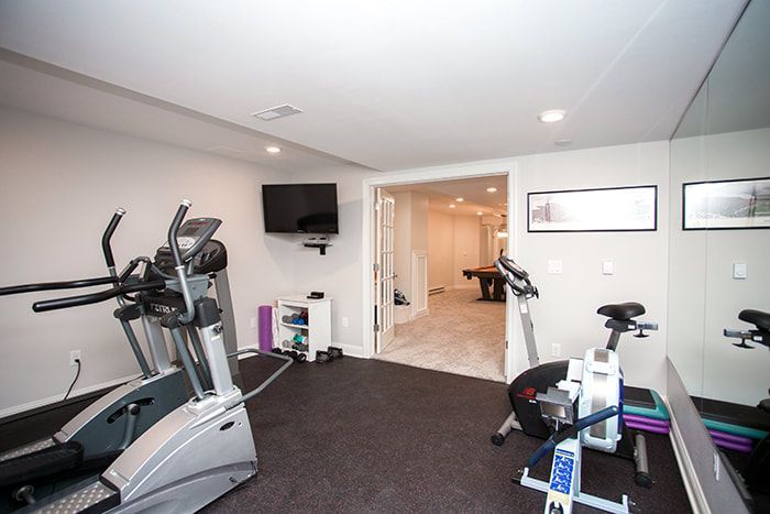 A gym with a treadmill , elliptical , exercise bike and a television.