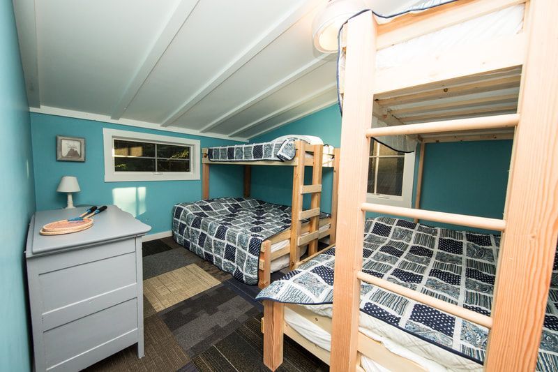 A bedroom with three bunk beds and a dresser.