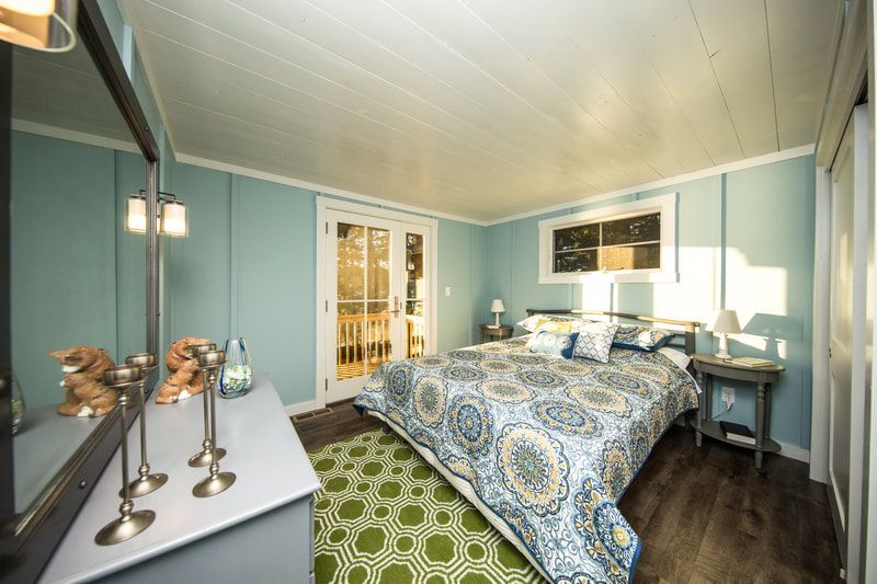 A bedroom with a large bed , dresser , mirror and candles.