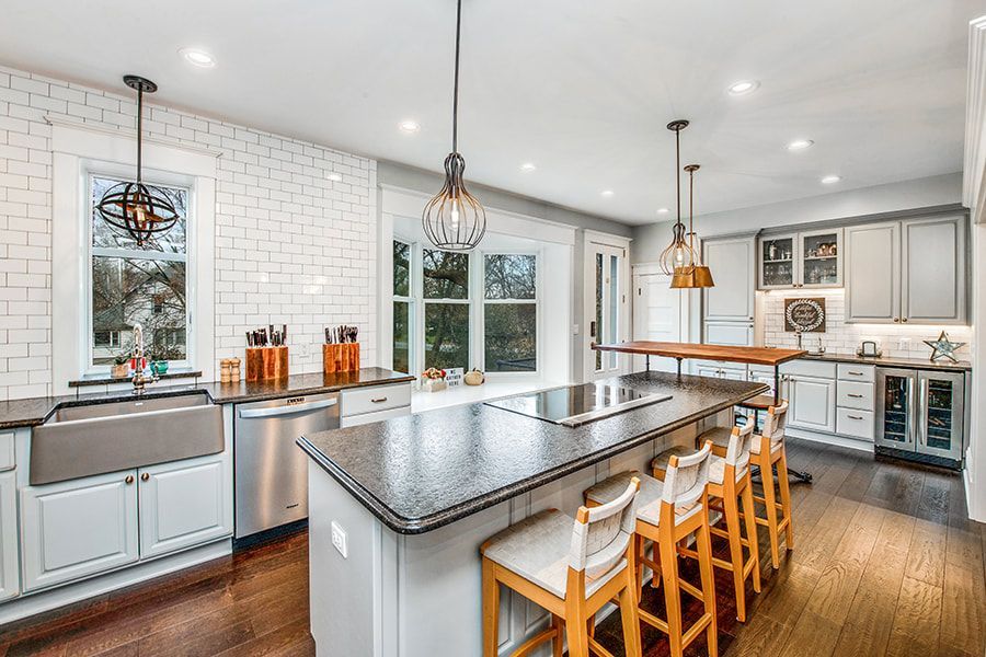A kitchen with white cabinets , stainless steel appliances , granite counter tops and a large island.
