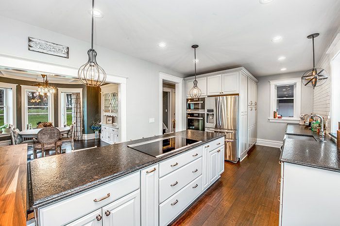 A kitchen with white cabinets , granite counter tops , and stainless steel appliances.