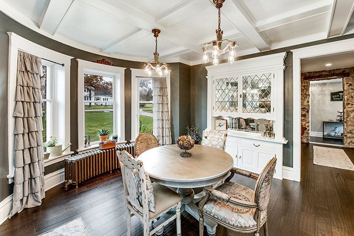 A dining room with a round table and chairs and a hutch.