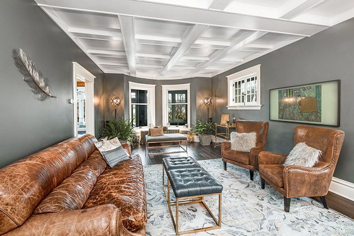 A living room with a brown leather couch , two chairs , and a coffee table.