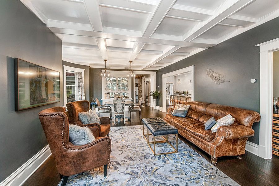 A living room with a couch , chairs , and a flat screen tv.