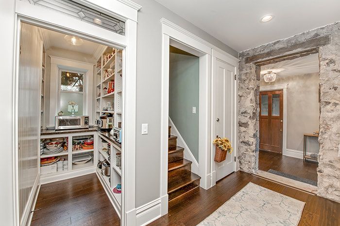 A hallway with a pantry and stairs in a house.
