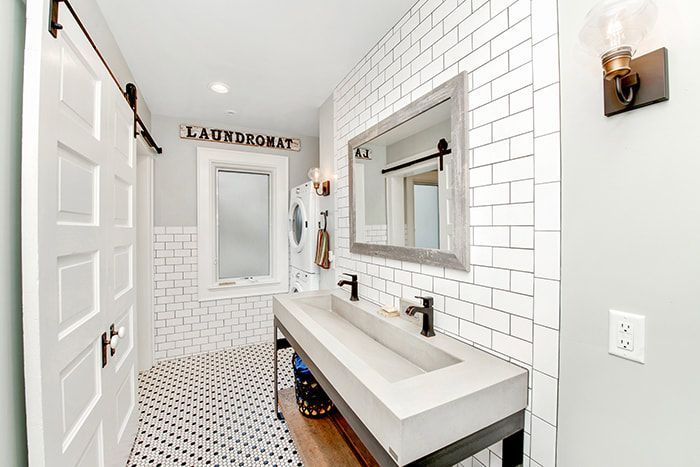 A bathroom with two sinks , a mirror and a sliding barn door.