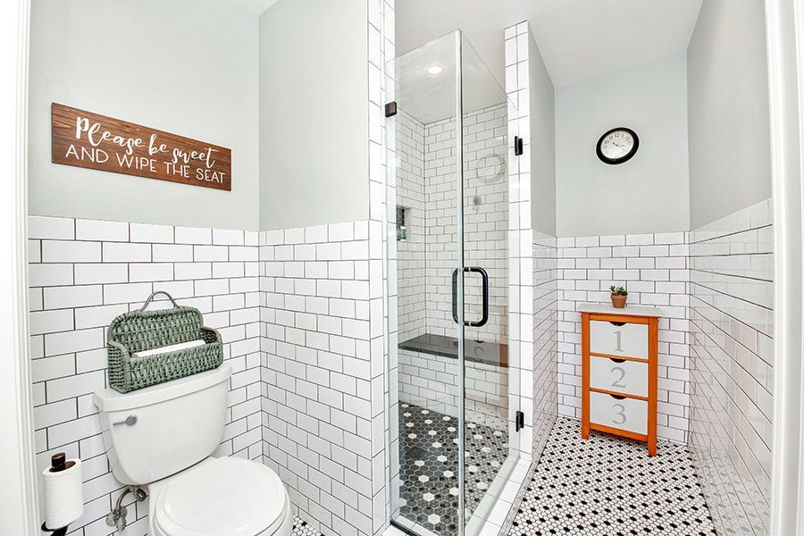 A bathroom with a toilet , shower and a sign on the wall.