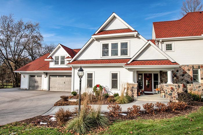 A large white house with a red roof is sitting on top of a lush green hillside.