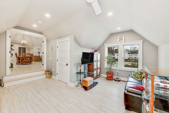 A living room with a couch , television , and a ceiling fan.