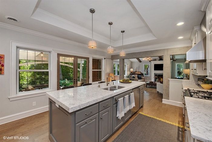 A kitchen with gray cabinets and white counter tops and a large island in the middle.