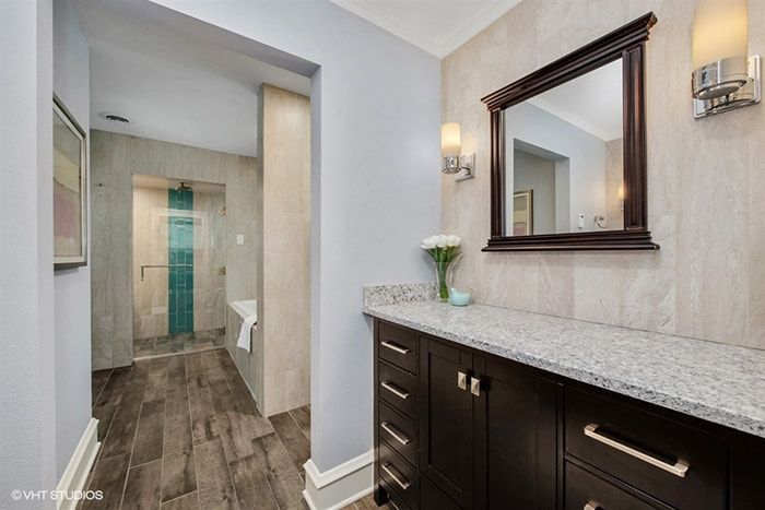 A bathroom with a sink , mirror and walk in shower.