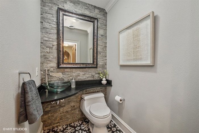 A bathroom with a toilet , sink and mirror.