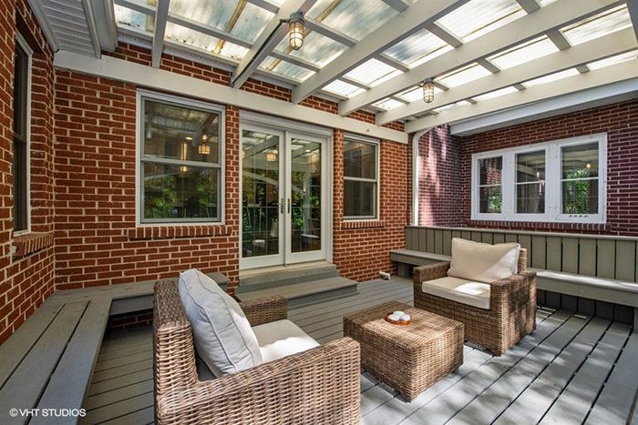 A patio with wicker furniture and a glass roof.