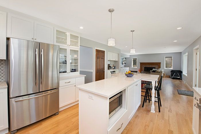 A kitchen with stainless steel appliances , white cabinets , and a large island.