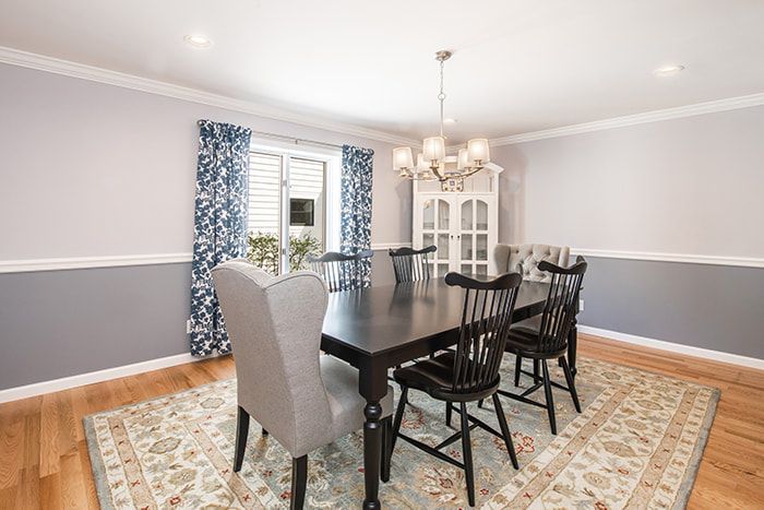 A dining room with a table and chairs and a rug.