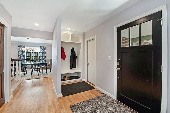 A hallway in a house with a black door and a rug.