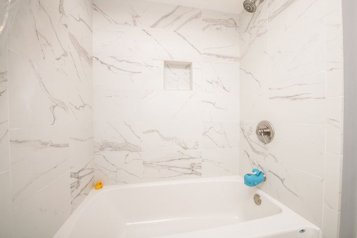 A bathroom with a bathtub , shower , and marble walls.