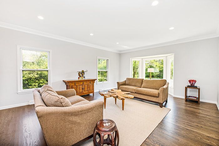 A living room with two couches , two chairs , a coffee table and a dresser.