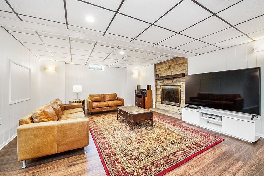 A living room with two couches , a fireplace , and a flat screen tv.
