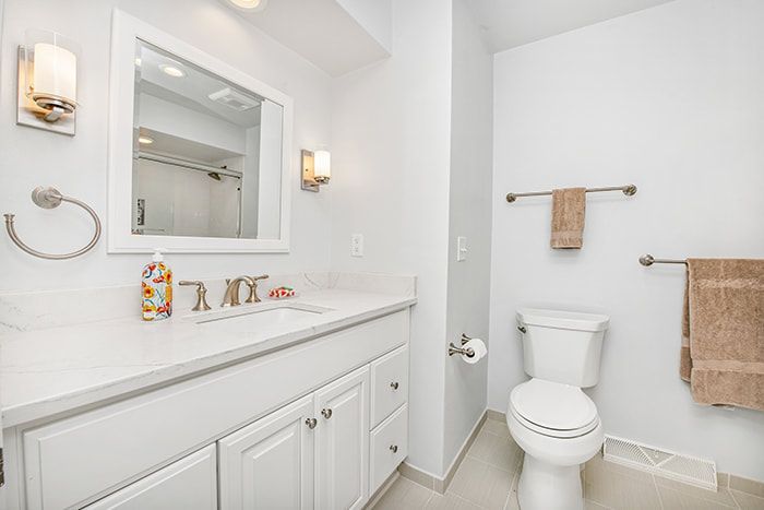 A bathroom with a toilet , sink and mirror.