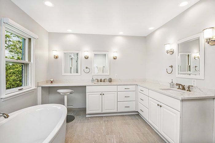 A bathroom with a tub , sink , mirror and cabinets.