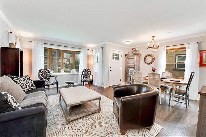 A living room with a couch , chairs , coffee table and dining table.