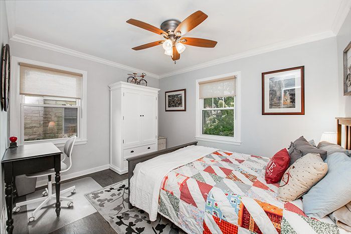 A bedroom with a bed , desk , and ceiling fan.