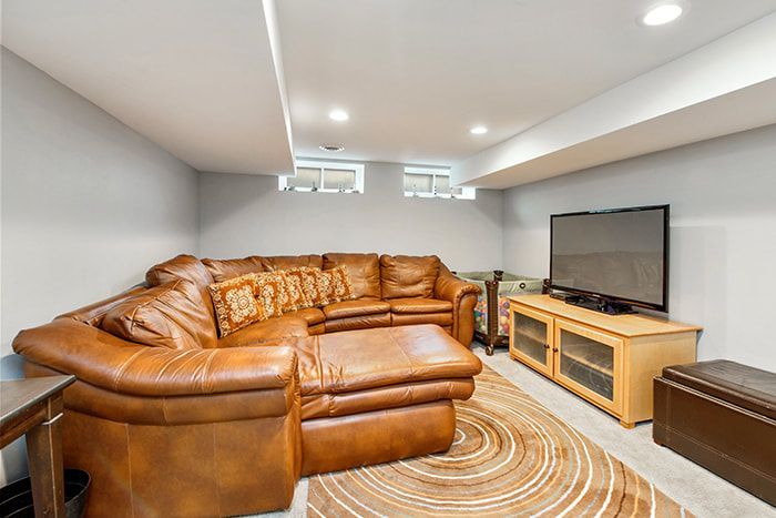 A living room with a brown leather sectional couch and a flat screen tv.