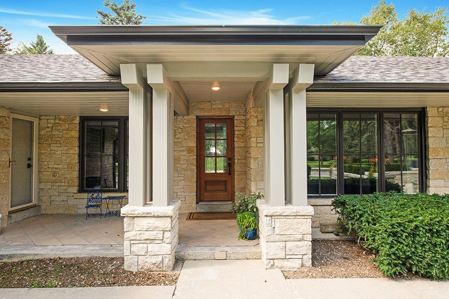 The front of a house with a large porch and a wooden door.