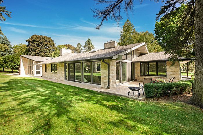 A large brick house with a large lawn in front of it.