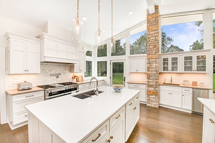 A kitchen with white cabinets , stainless steel appliances , and a large island.