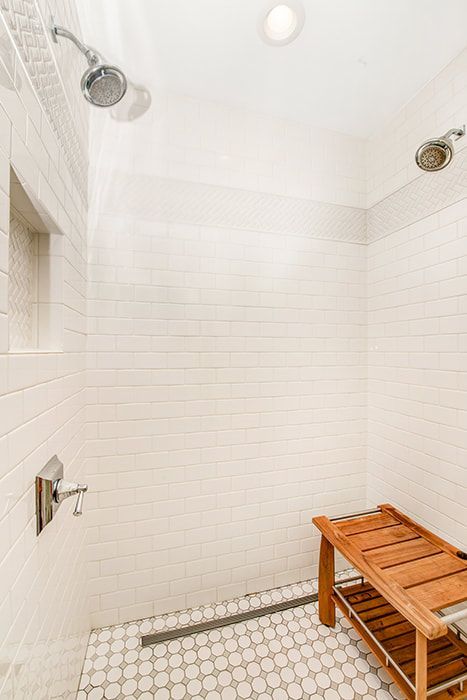 A bathroom with a walk in shower and a wooden bench.