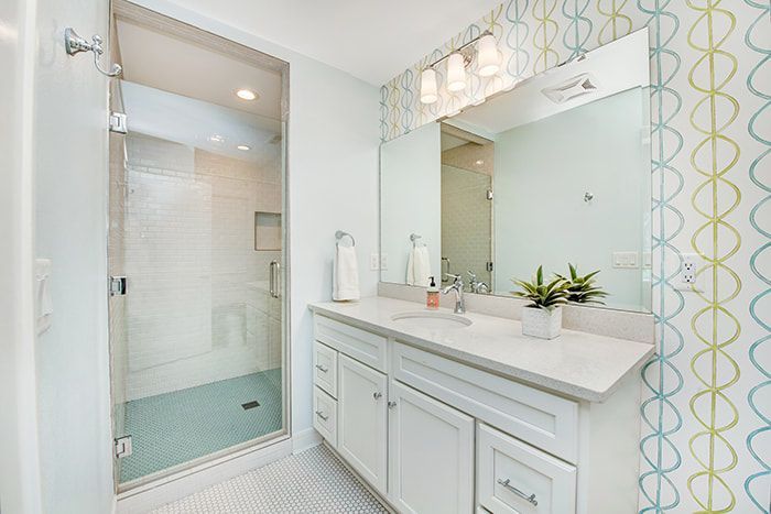 A bathroom with two sinks , a shower and a mirror.