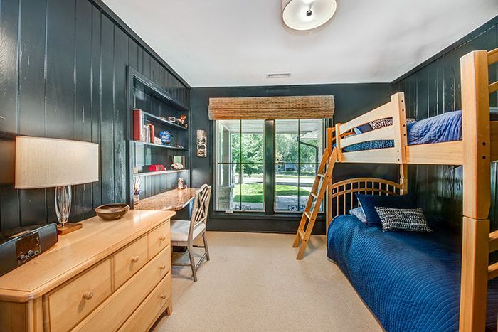A bedroom with bunk beds , a desk , and a dresser.