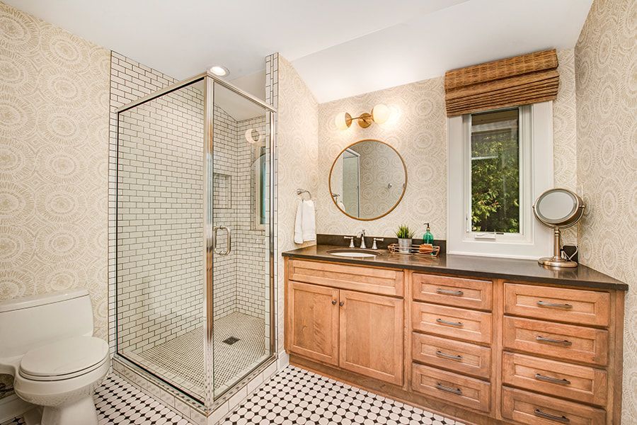 A bathroom with a toilet , sink , mirror and walk in shower.