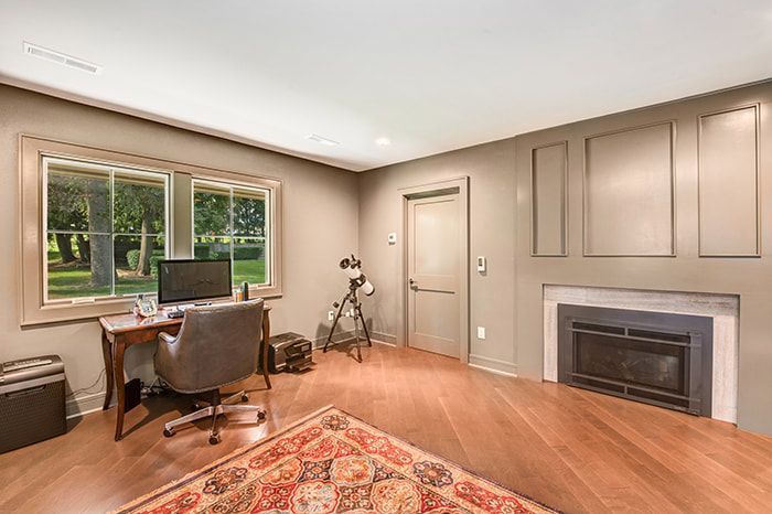 A living room with a desk , chair , computer and fireplace.