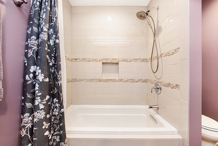 A bathroom with a tub and shower with a floral shower curtain.