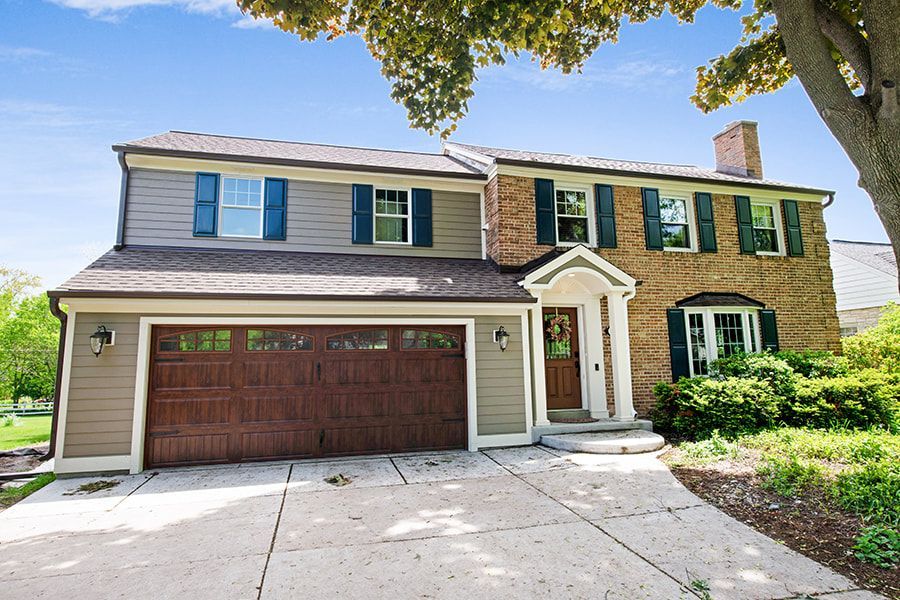 A large brick house with a brown garage door
