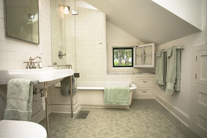A bathroom with a tub , sink , toilet and mirror.