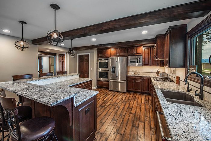 A kitchen with granite counter tops , stainless steel appliances , wooden cabinets , and a large island.