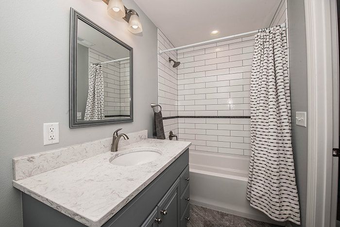A bathroom with a sink , mirror , tub and shower.