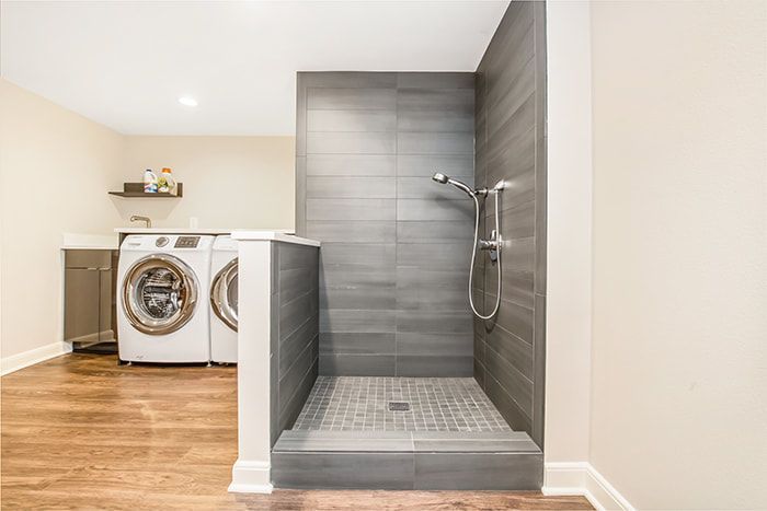 A laundry room with a washer and dryer and a walk in shower.