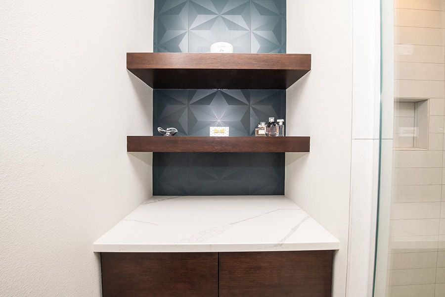 A bathroom with three shelves and a sink.