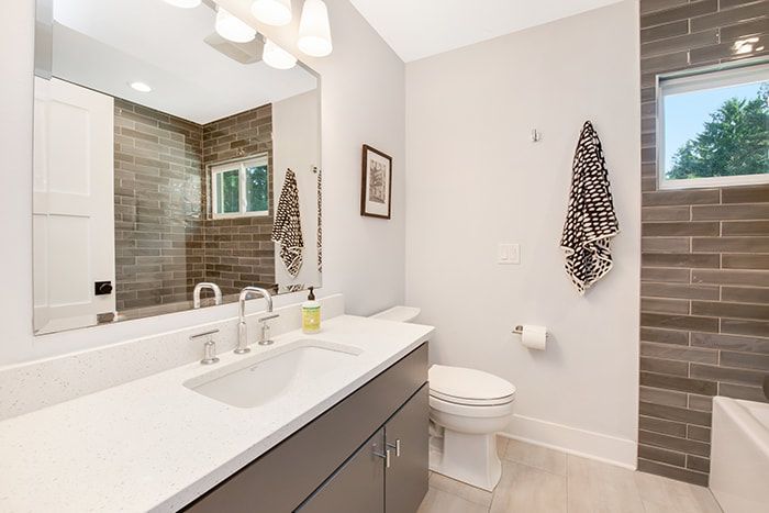 A bathroom with a toilet , sink , and mirror.