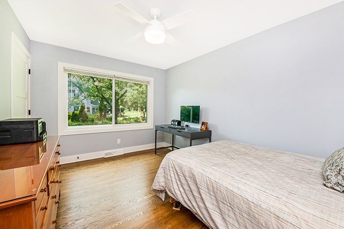 A bedroom with a bed , desk , dresser and window.