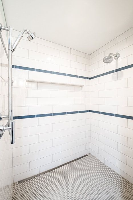 A bathroom with white tiles and a walk in shower.