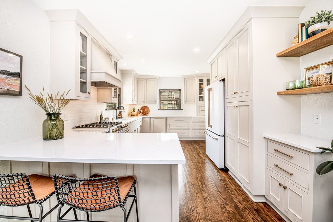 A kitchen with white cabinets , hardwood floors , a refrigerator and a sink.
